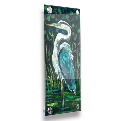 A painting of a great blue heron standing tall in a pond surrounded by vibrant foliage. Printed on acrylic.