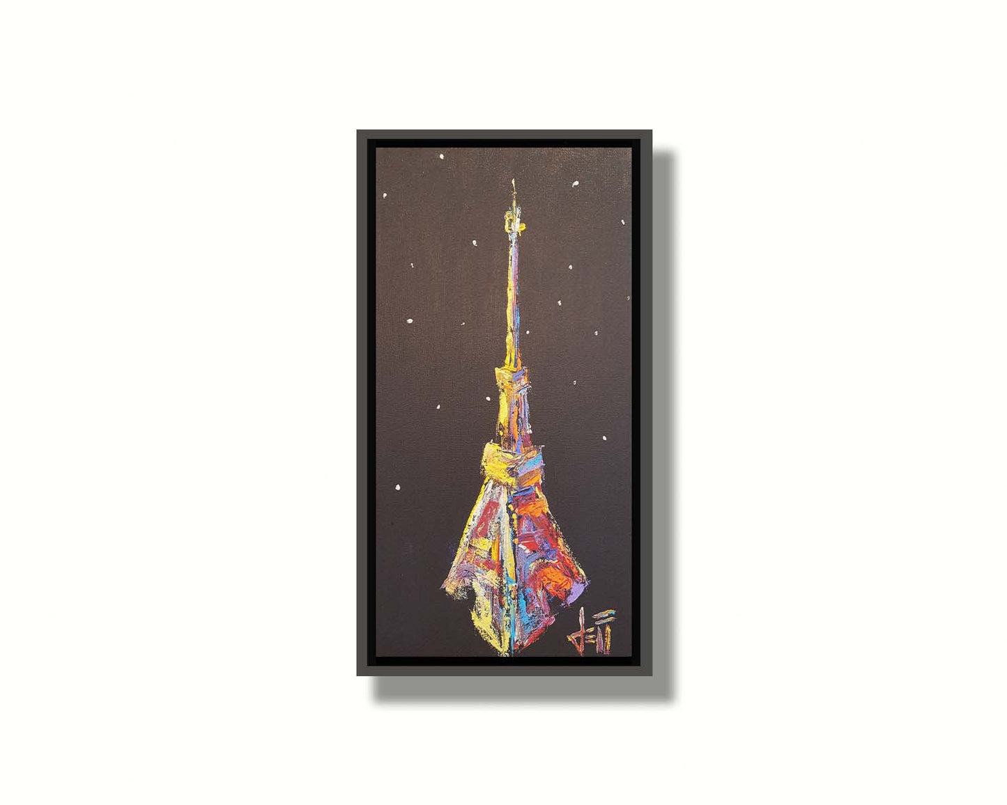 A painting of an abstracted rendition of the iconic Eiffel Tower in bright colors against a black background with white speckles. Printed on canvas in a float frame.