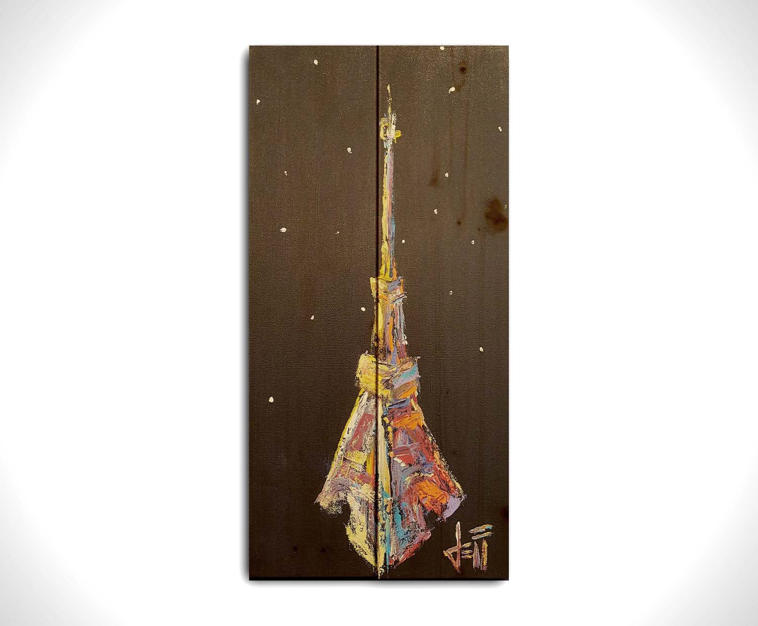 A painting of an abstracted rendition of the iconic Eiffel Tower in bright colors against a black background with white speckles. Printed on a wood pallet.