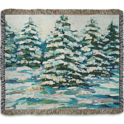 A woven throw blanket decorated with the print of a painting of a snowy evergreen forest, textured with thick layers of paint. 