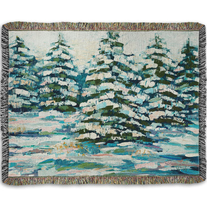 A woven throw blanket decorated with the print of a painting of a snowy evergreen forest, textured with thick layers of paint. 