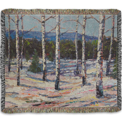 Woven throw blanket printed with a painting of birch trees in a snowy landscape with mountains in the background.