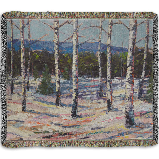 Woven throw blanket printed with a painting of birch trees in a snowy landscape with mountains in the background.