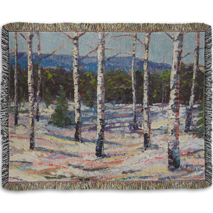 Woven throw blanket printed with a painting of birch trees in a snowy landscape with mountains in the background.