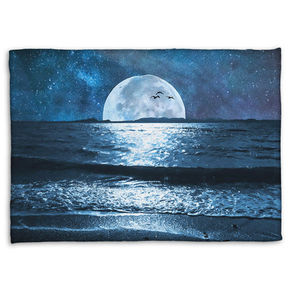 A coral fleece throw blanket designed with a photo of a full moon over the horizon of a calm, dark sea during a starry night.