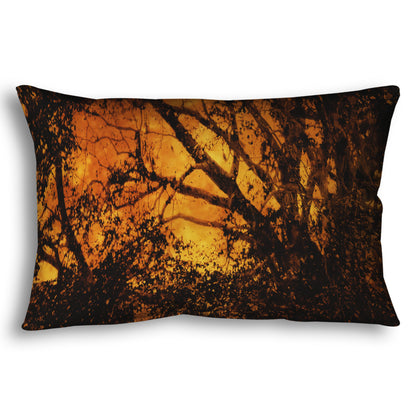 A throw pillow designed with a photo of the black shadow of a tree superimposed over a bright orange full moon.