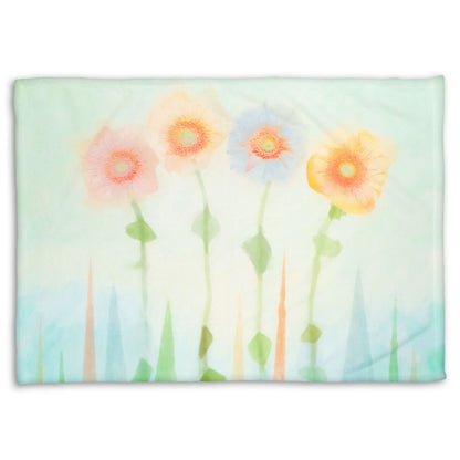 A coral fleece blanket designed with an edited photo of flowers, the stems and background of trees illustrated to look like watercolor.