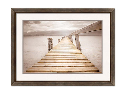 A photo looking along a pier out into the water, edited in a sepia tone. Printed on paper, matted, and framed.