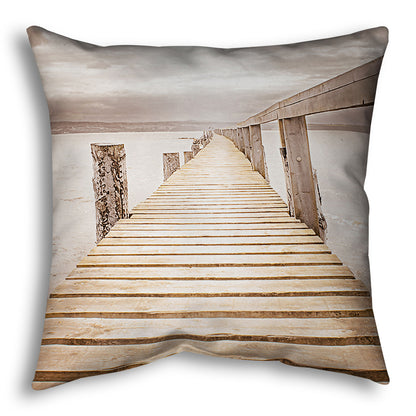 A throw pillow designed with a photo looking along a pier out into the water, edited in a sepia tone.