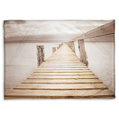 A fleece throw blanket designed with a photo looking along a pier out into the water, edited in a sepia tone.