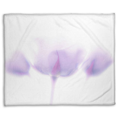 A fleece throw blanket designed with a  photo of three pale purple roses against a pure white background, enveloped in a gentle white glow.
