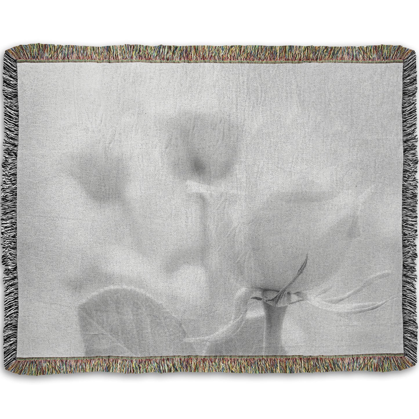 A woven throw blanket designed with a grayscale photo of three roses bathed in a soft white light. 