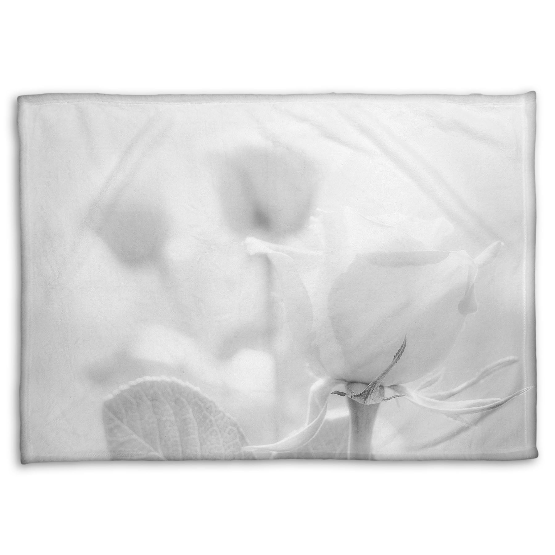 A fleece throw blanket designed with a grayscale photo of three roses bathed in a soft white light.