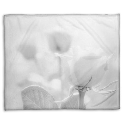 A fleece throw blanket designed with a grayscale photo of three roses bathed in a soft white light.