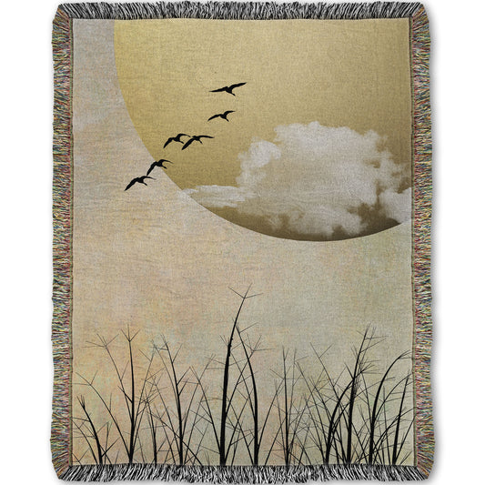 Woven throw blanket designed with a photo collage of migratory birds flying south for the winter, silhouetted against a big gold moon. 