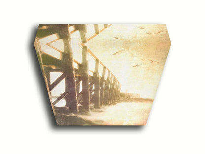 A sepia photo looking out to sea along the side of a pier, as seagulls fly above. Printed on canvas.