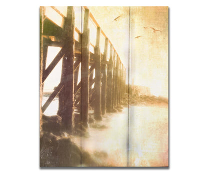 A sepia photo looking out to sea along the side of a pier, as seagulls fly above. Printed on a box board.