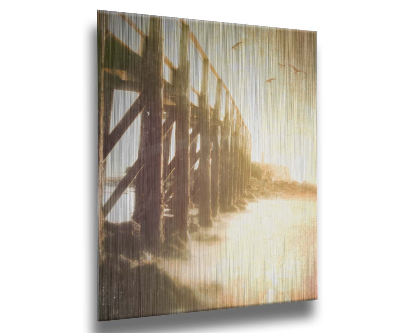 A sepia photo looking out to sea along the side of a pier, as seagulls fly above. Printed on metal.