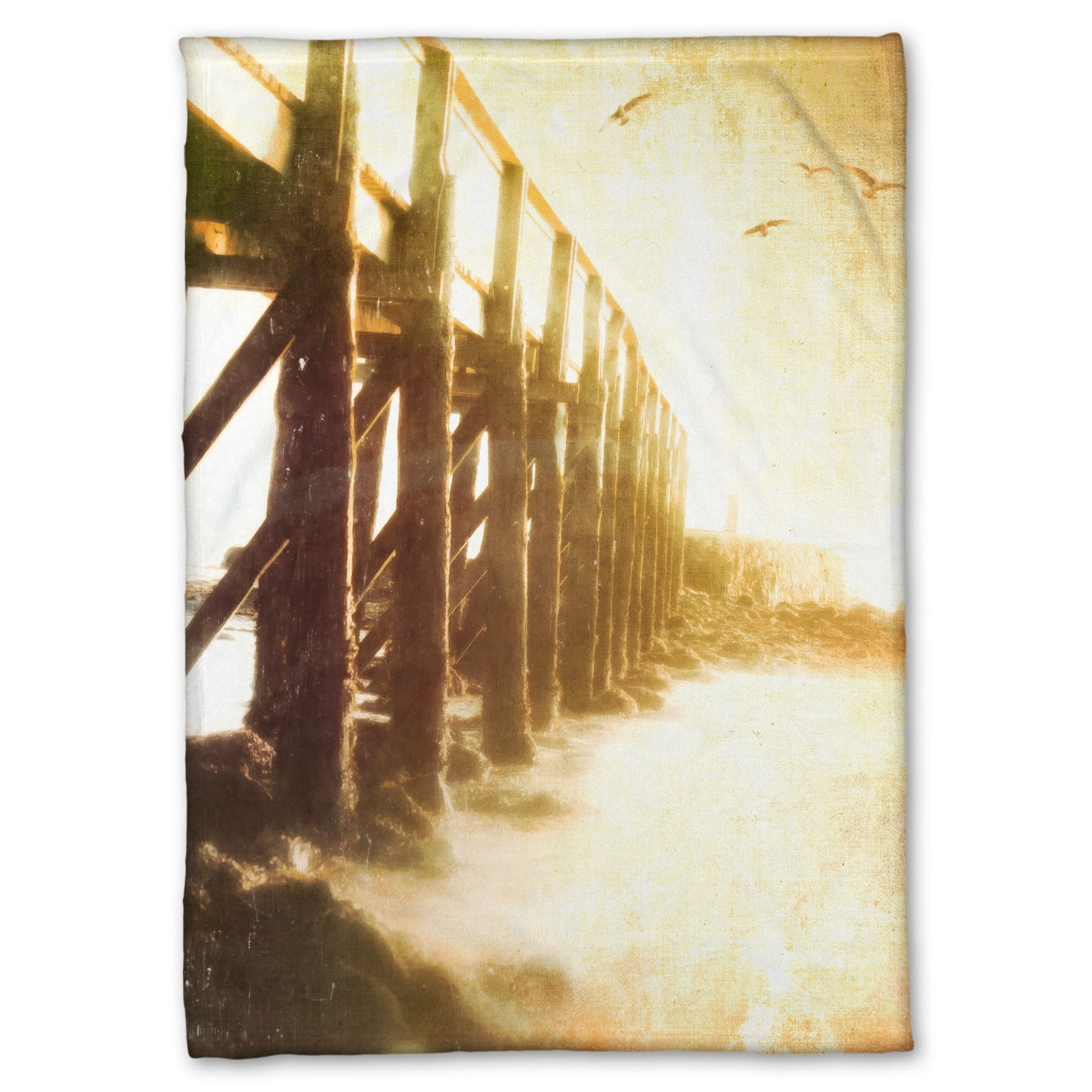 A fleece throw blanket designed with a sepia photo looking out to sea along the side of a pier, as seagulls fly above.