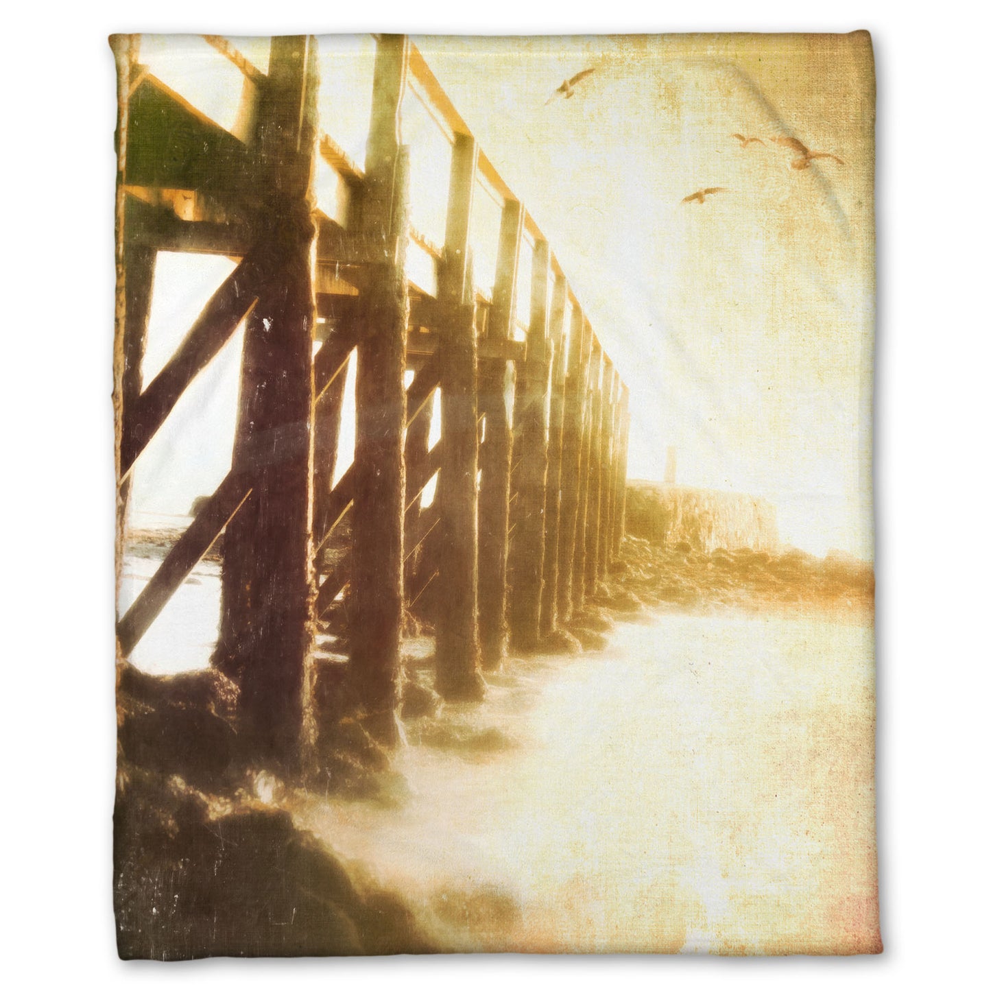 A fleece throw blanket designed with a sepia photo looking out to sea along the side of a pier, as seagulls fly above.