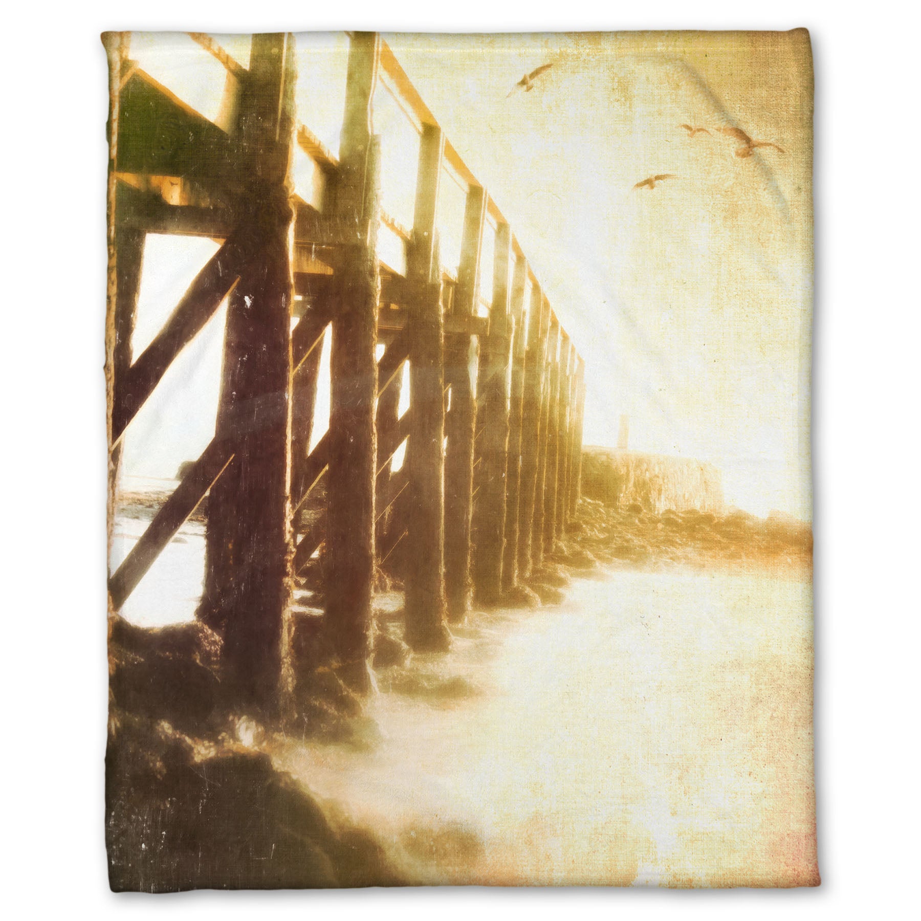 A fleece throw blanket designed with a sepia photo looking out to sea along the side of a pier, as seagulls fly above.