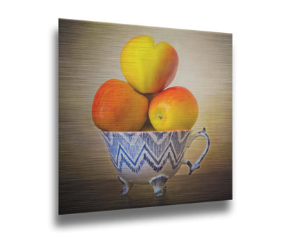 A photograph of a cup full of red and yellow apples, set against a brown table and lighter wall. Printed on metal.