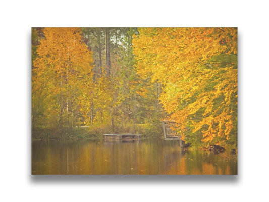 A photo of yellow autumn trees at a pond, their leaves reflecting off the water. Printed on canvas.