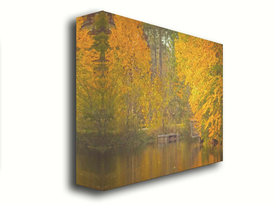 A photo of yellow autumn trees at a pond, their leaves reflecting off the water. Printed on canvas.