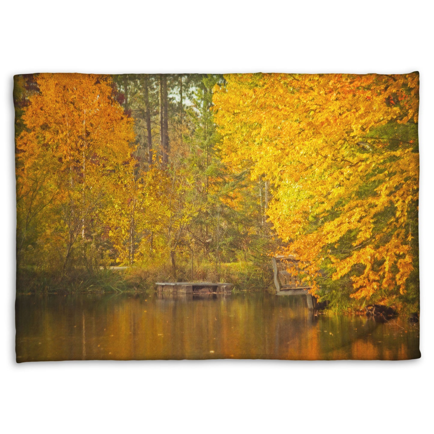 A fleece throw blanket designed with a photo of yellow autumn trees at a pond, their leaves reflecting off the water. 