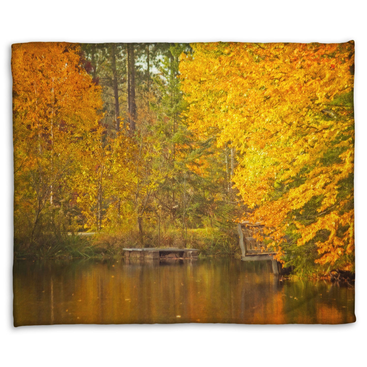 A fleece throw blanket designed with a photo of yellow autumn trees at a pond, their leaves reflecting off the water. 