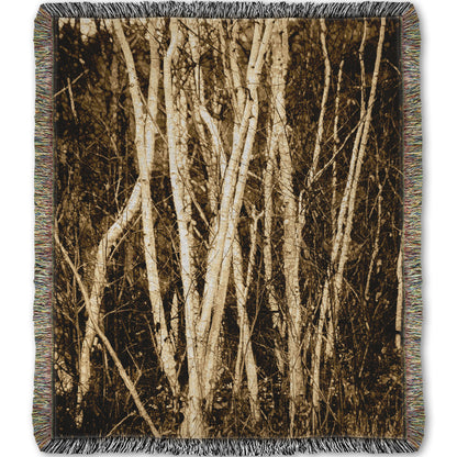 A woven throw blanket designed with a sepia photo of a cluster of birch trees.