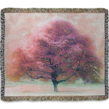 A woven throw blanket designed with an edited photo of a beech tree, its leaves pink for autumn. It has been modified to have a painterly look.
