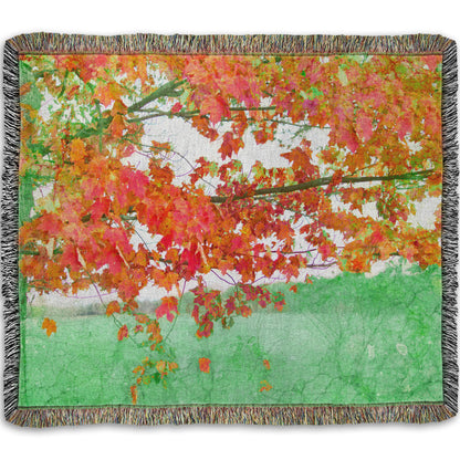 A woven throw blanket designed with a photo of a tree's red leaves. The rest of the image has been edited green.
