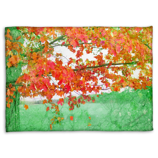 A fleece blanket designed with a photo of a tree's red leaves. The rest of the image has been edited green.