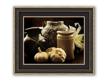 A photo of a still life arrangement of pottery and plants with a dark, warm palette. Printed on paper, matted, and framed.