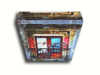 A photo of a bike propped up on a balcony in front of a red door. Printed on canvas.