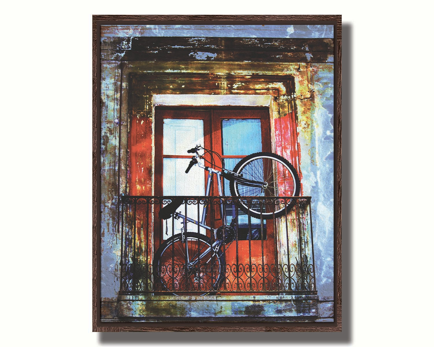 A photo of a bike propped up on a balcony in front of a red door. Printed on canvas in a float frame.