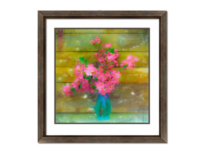 A photograph of a blue vase of bright pink flower blossoms against a yellow painted wooden wall. Printed on paper, matted, and framed.