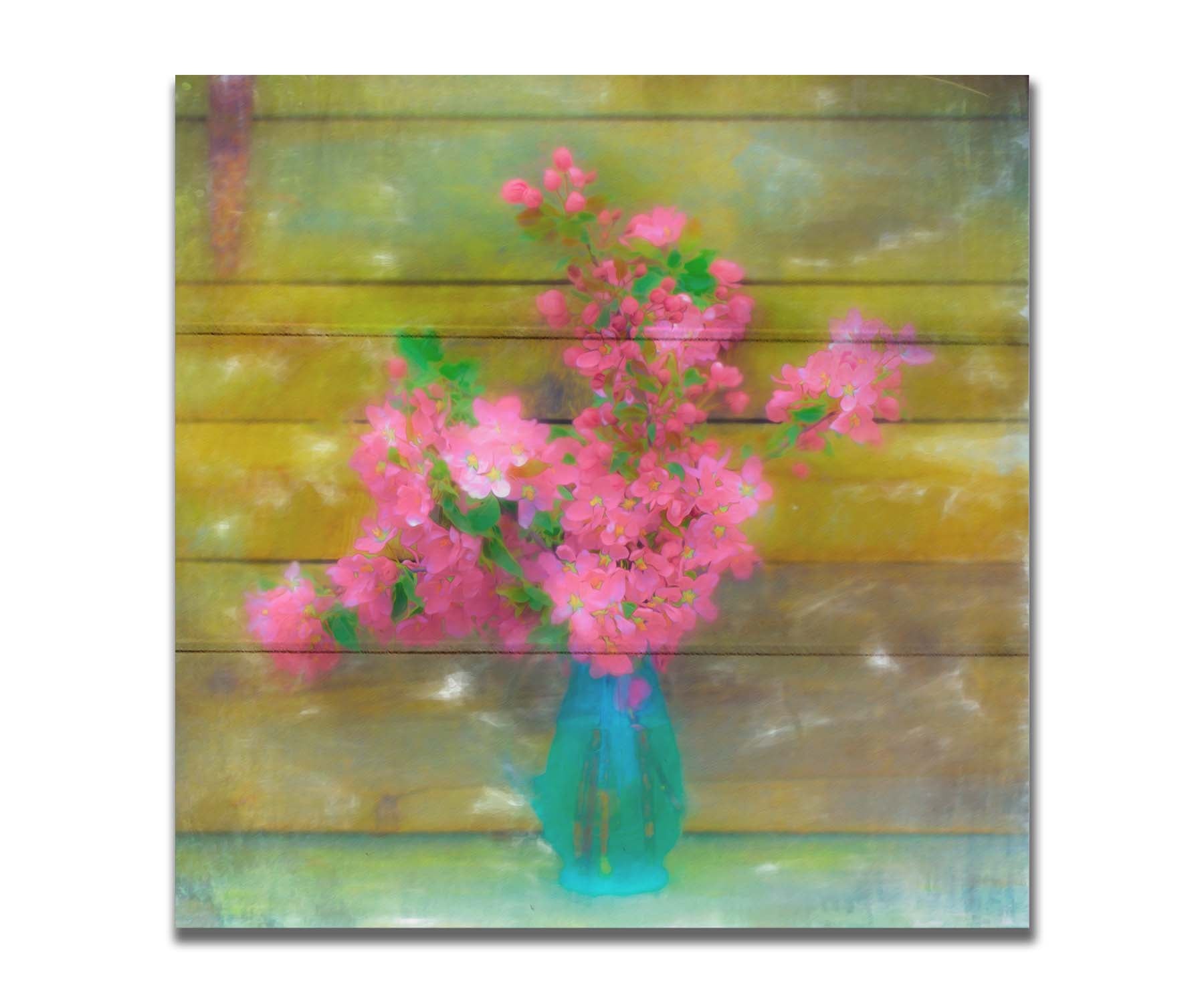 A photograph of a blue vase of bright pink flower blossoms against a yellow painted wooden wall. Printed on a box board.