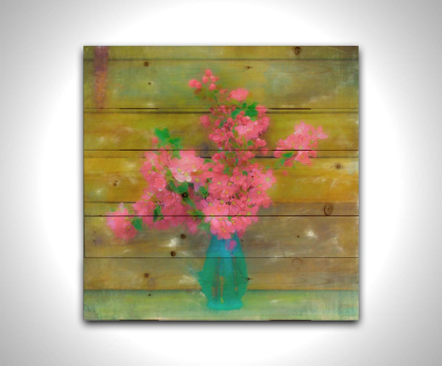 A photograph of a blue vase of bright pink flower blossoms against a yellow painted wooden wall. Printed on a wood pallet.