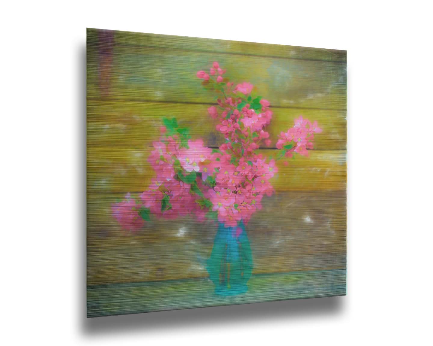 A photograph of a blue vase of bright pink flower blossoms against a yellow painted wooden wall. Printed on metal.