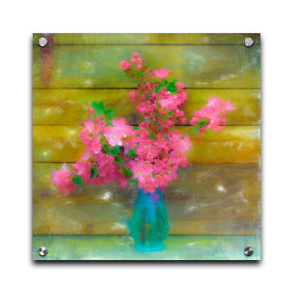 A photograph of a blue vase of bright pink flower blossoms against a yellow painted wooden wall. Printed on acrylic.