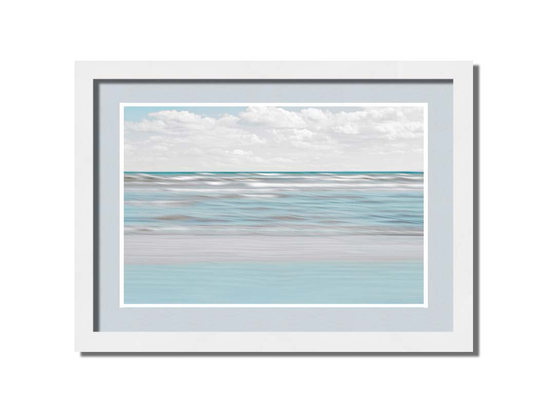 A photo of the ocean, and the line formed at the horizon where its color cuts across the sky of fluffy, white clouds. Printed on paper, matted, and framed.