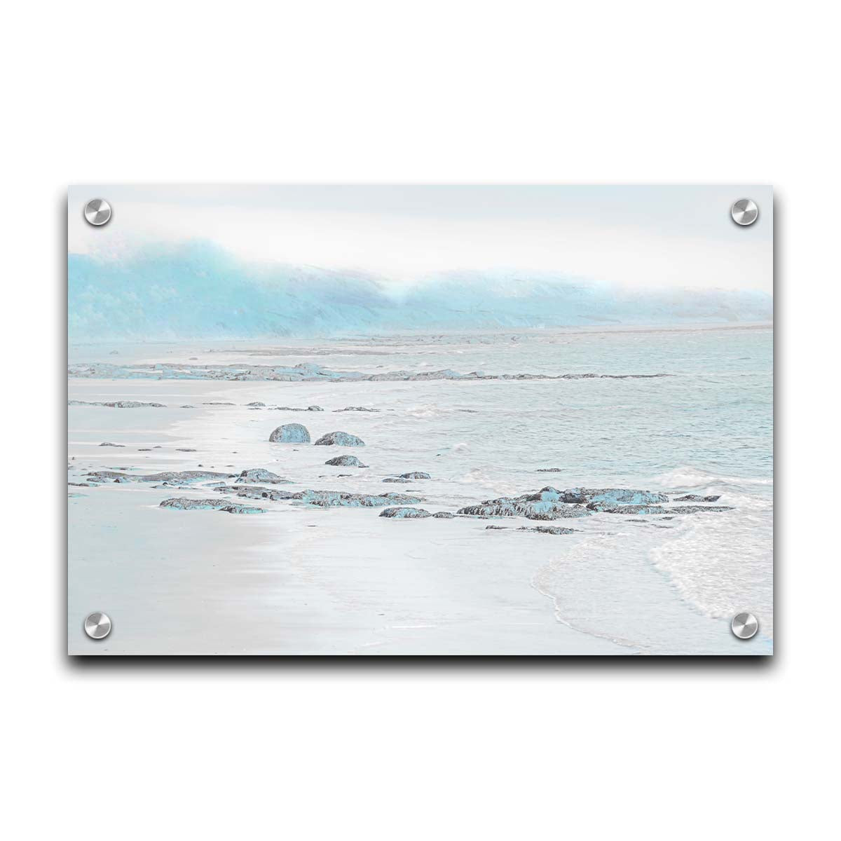 A photo of a rocky beach with a pale blue palette. The sea is calm and washing over the sand and rocks. Printed on acrylic.