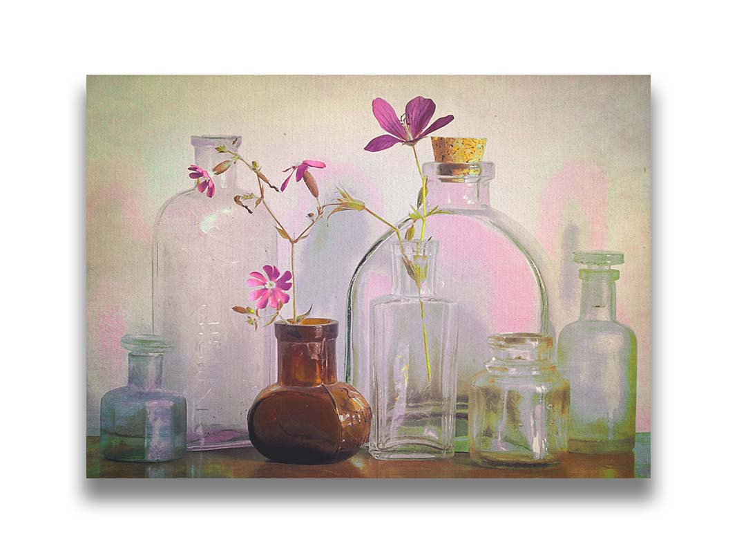 A photo of a selection of glass bottles and vases, sitting on a table. Sprigs of pink flowers rest in a few of the bottles. Printed on canvas.