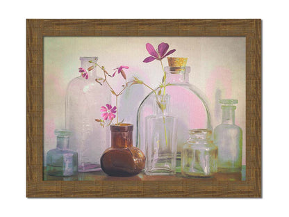 A photo of a selection of glass bottles and vases, sitting on a table. Sprigs of pink flowers rest in a few of the bottles. Printed on canvas and framed.