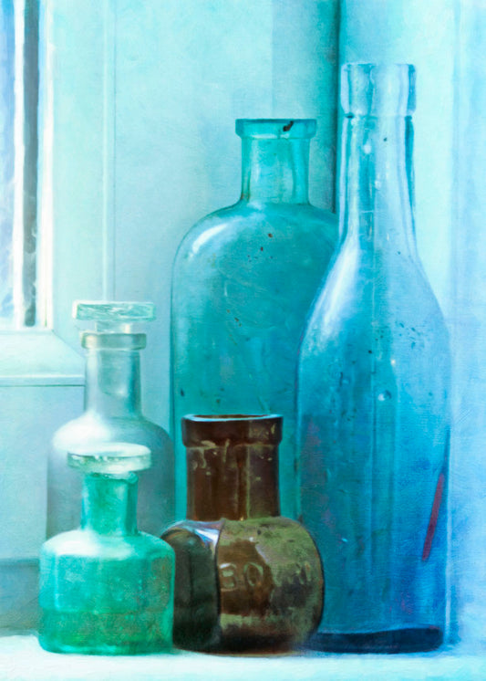 A photo of an assortment of blue and brown bottles, sitting in the corner on a window stool.
