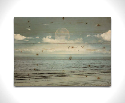 A photo of a pale blue sea with a lage moon on the horizon. Printed on a wood pallet.