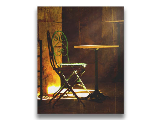 A photo of chairs around a small table, illuminated by light pouring in through the window. Printed on canvas.