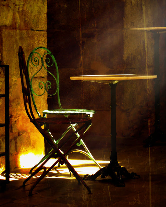 A photo of chairs around a small table, illuminated by light pouring in through the window. 